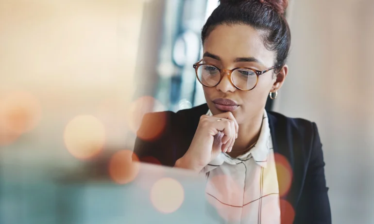 A professional woman with glasses working at a laptop