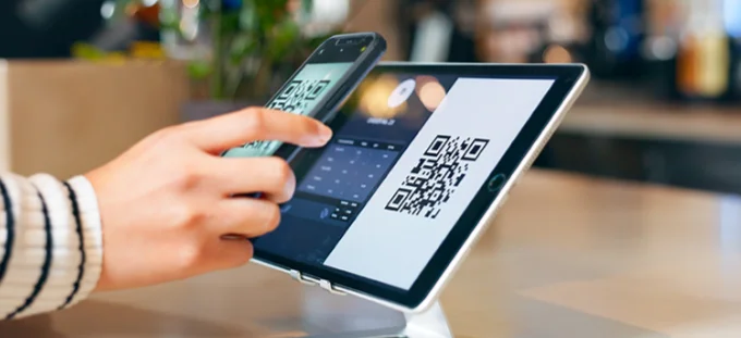 A woman using mobile phone payment at a checkout terminal
