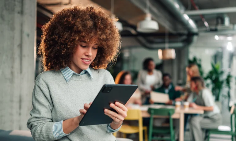 A woman using a tablet with a group of collaborating colleagues in the background