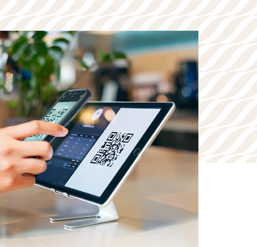 Someone using a phone to tap a payment on a checkout tablet