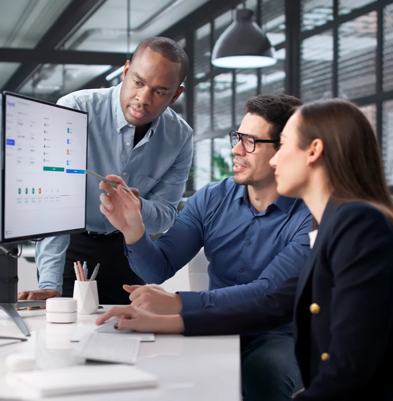 Colleagues collaborating in front of a computer with many charts and graphics displayed